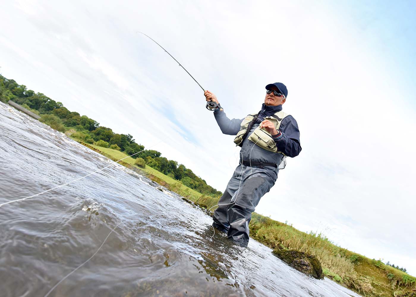 Mies seisoo joessa ja heittää onkea.